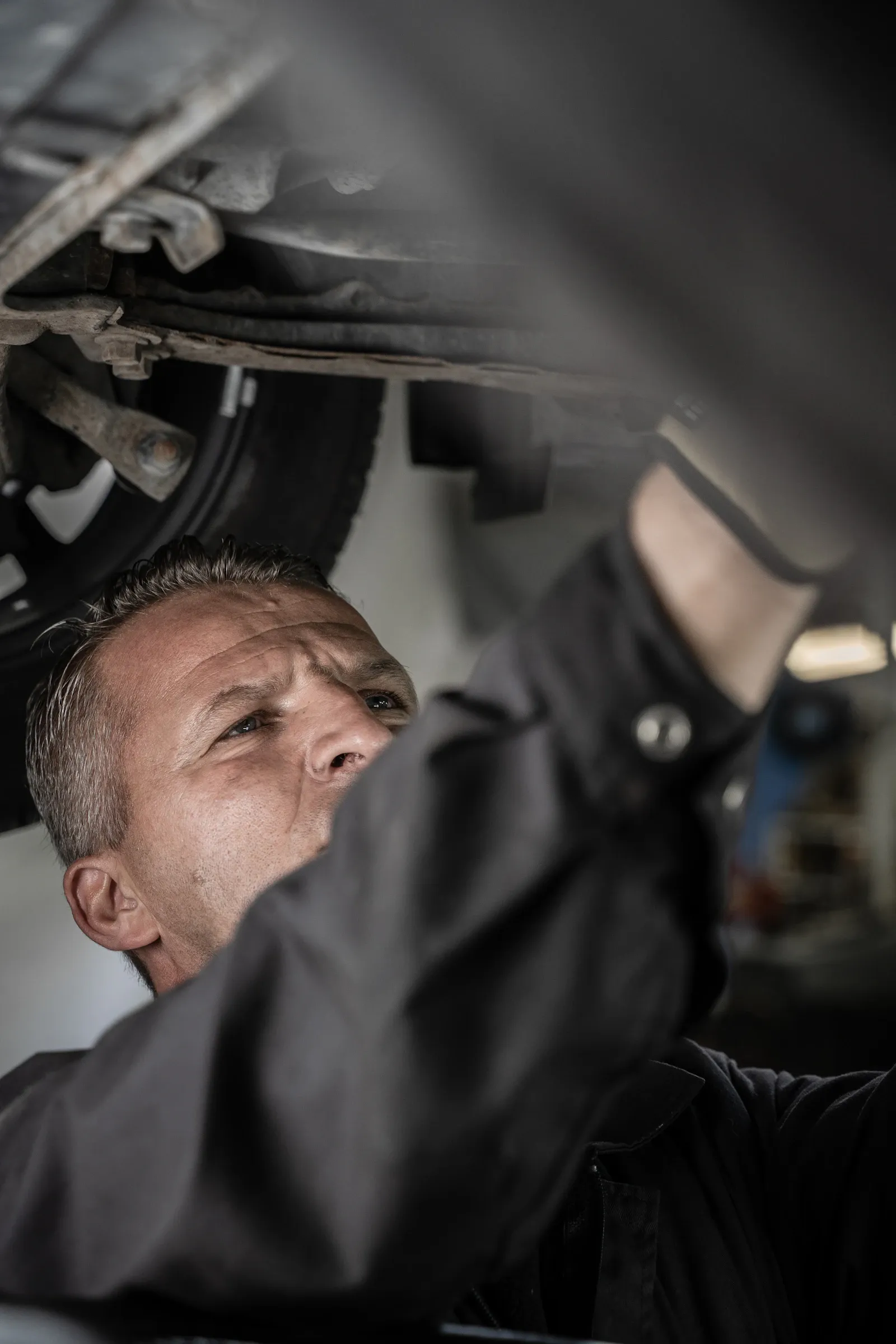 Mechanic inspecting the underside of a vehicle for a transfer case fluid leak