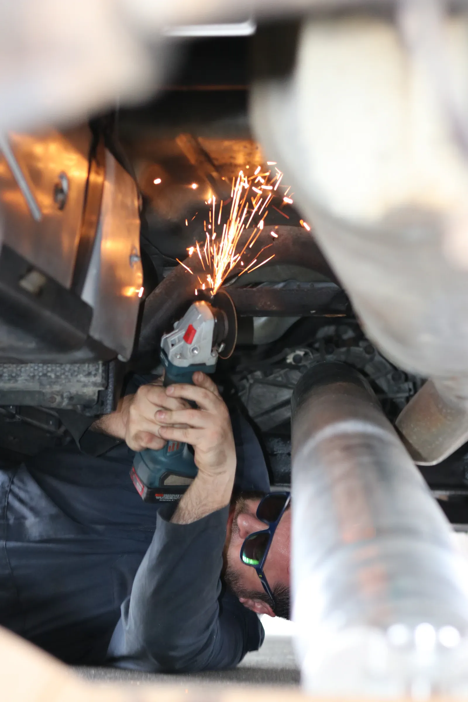 Mechanic working beneath a vehicle near the driveshaft and driveline