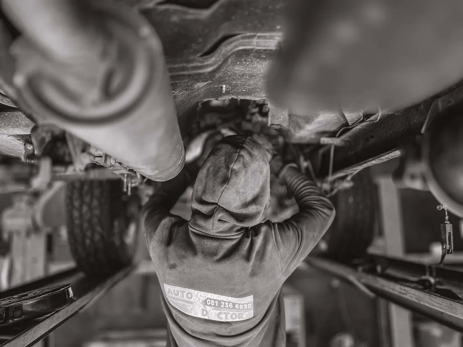 Mechanic inspecting a vehicle driveline and differential area in a workshop