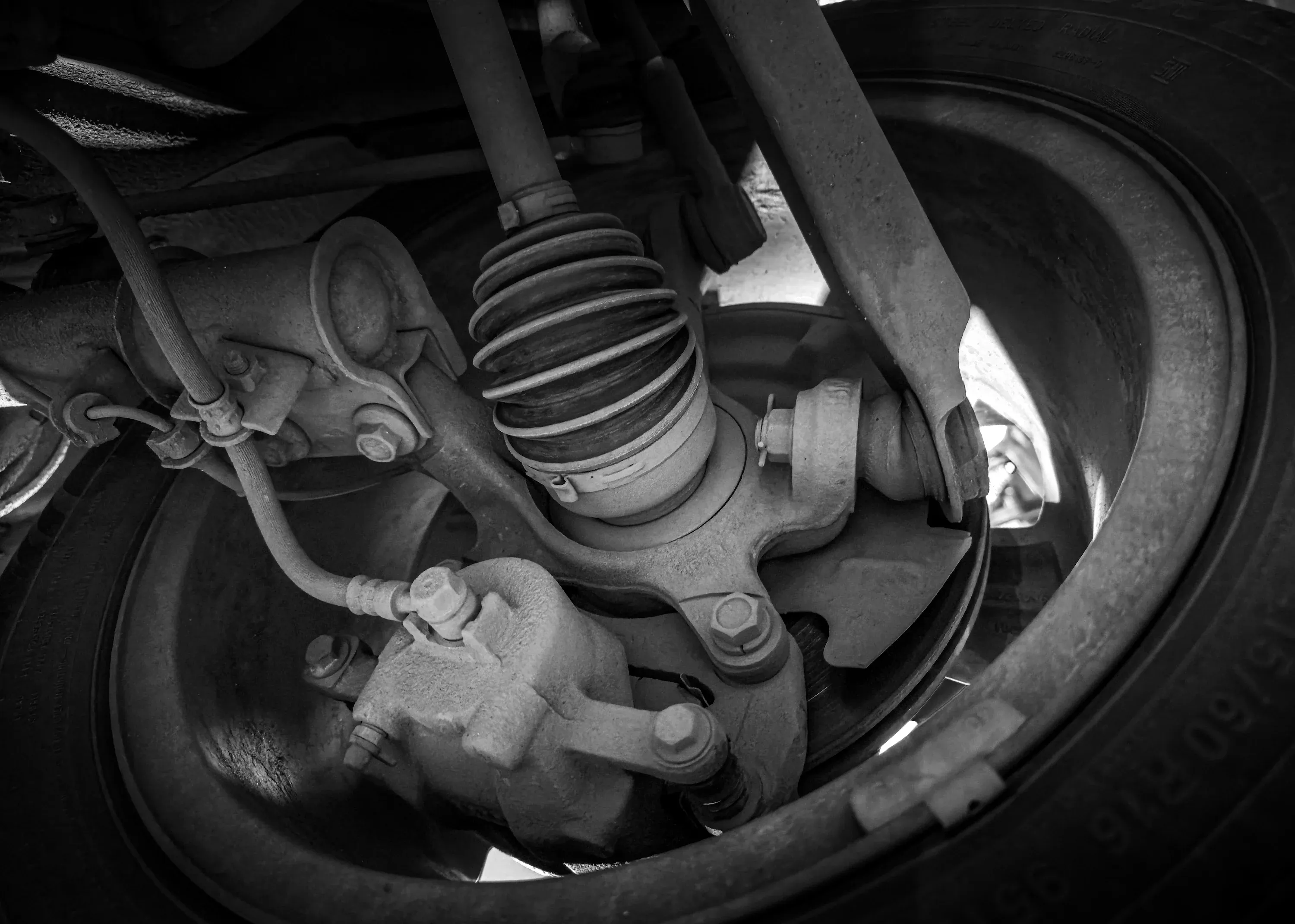 Close-up of a vehicle CV axle, suspension and wheel assembly in a repair workshop