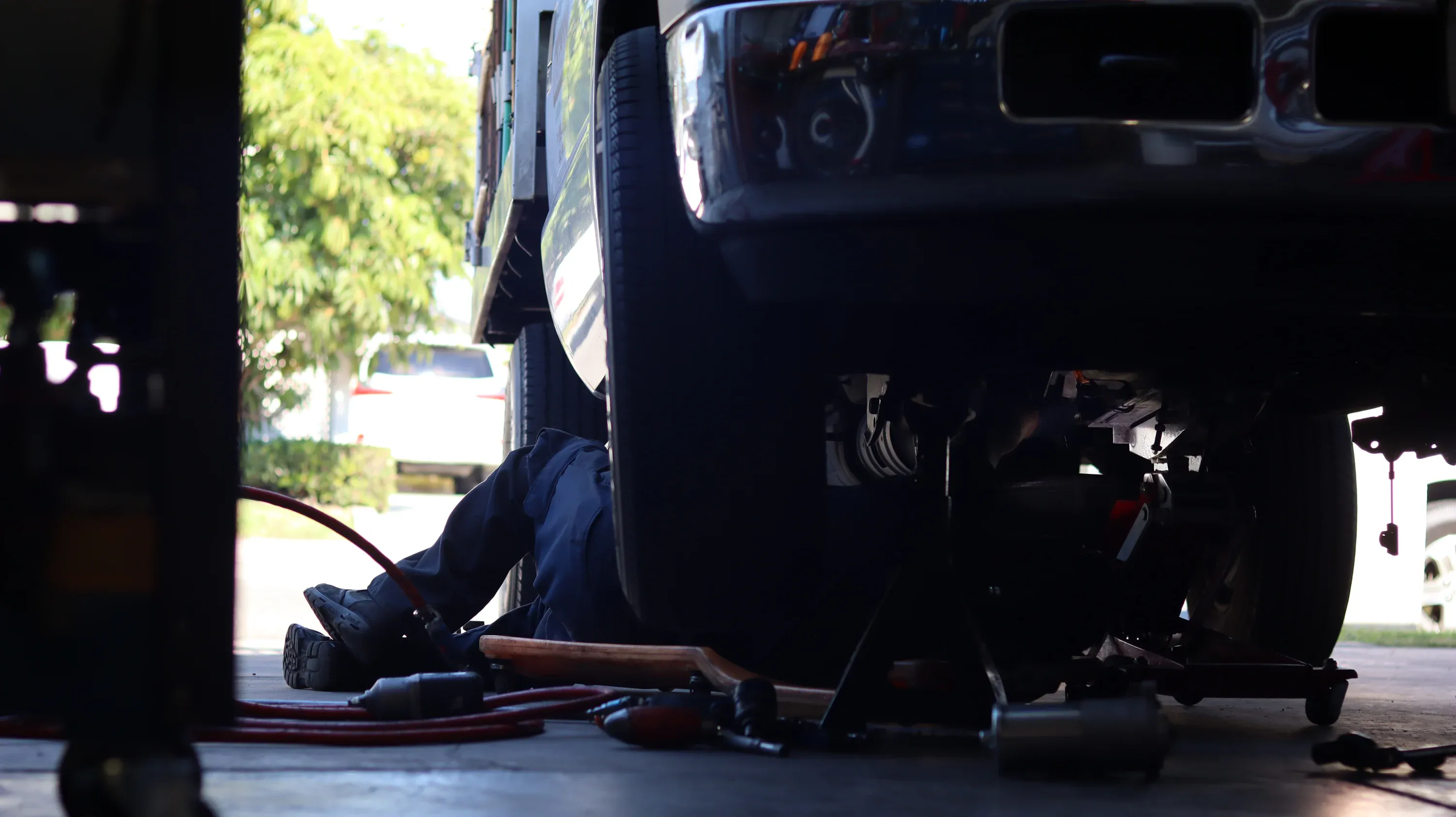 Mechanic inspecting the underside and rear driveline of a vehicle on a lift