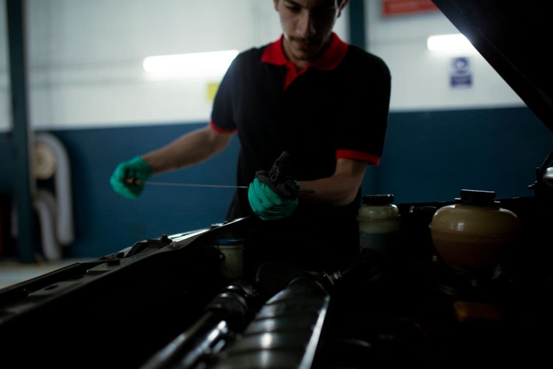Mechanic checking engine oil with a dipstick in a workshop