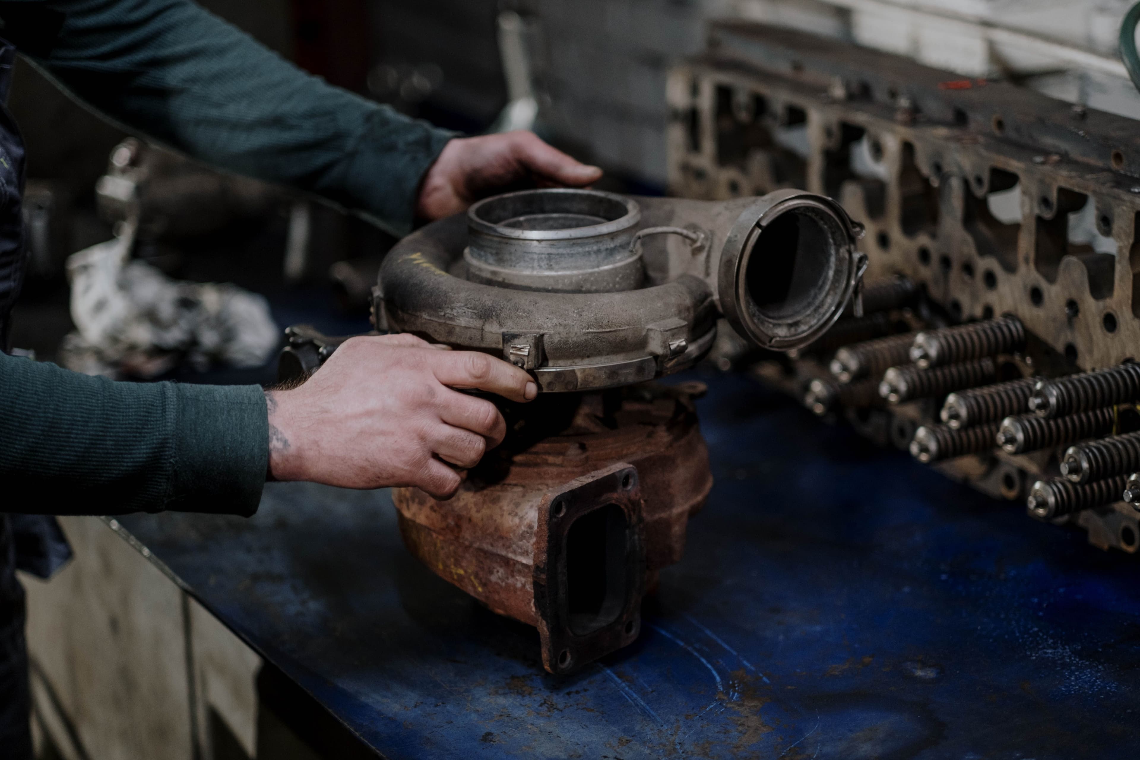 Mechanic holding and inspecting a turbocharger in an automotive workshop