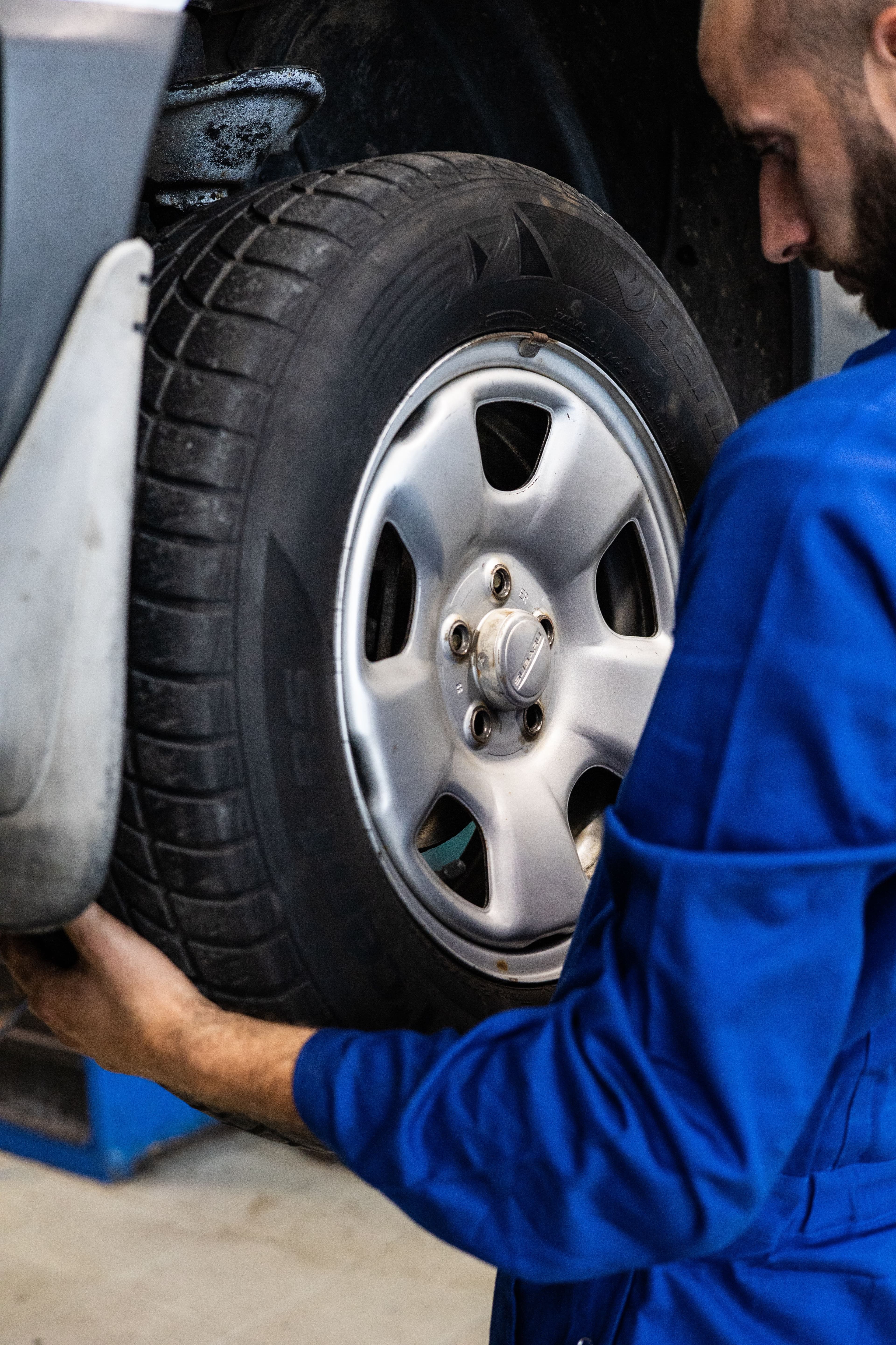 Mechanic inspecting a car wheel and hub area in a repair shop
