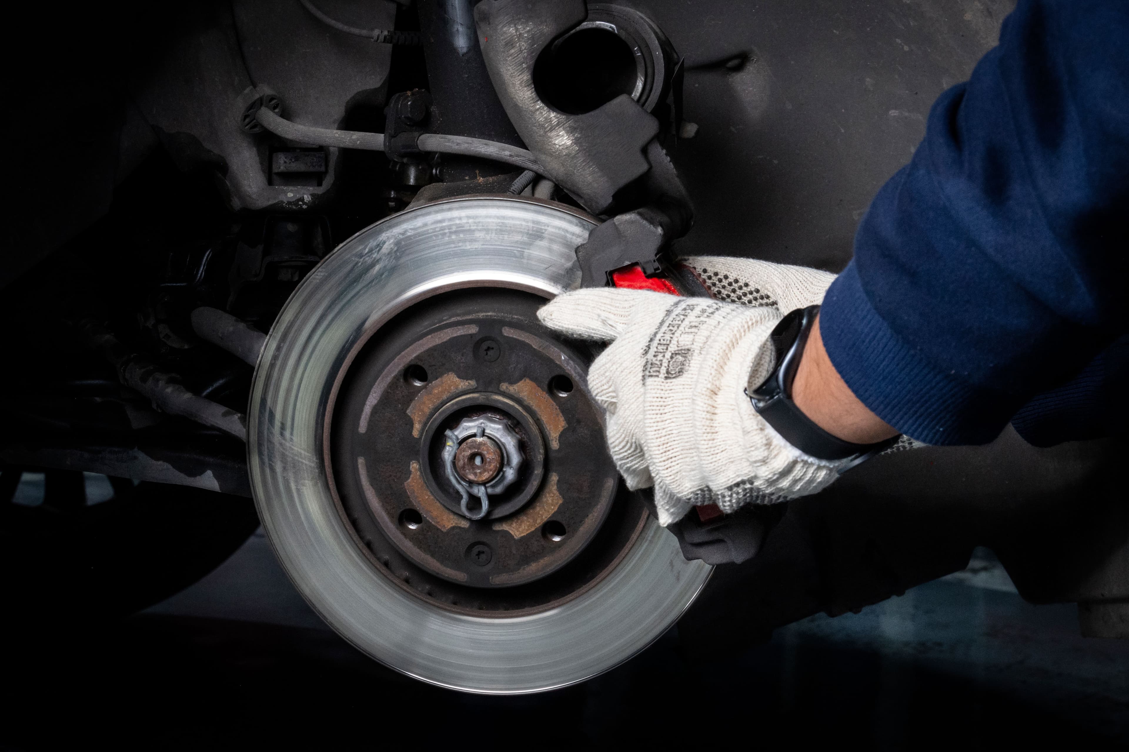 Mechanic servicing a vehicle brake disc and caliper in a workshop