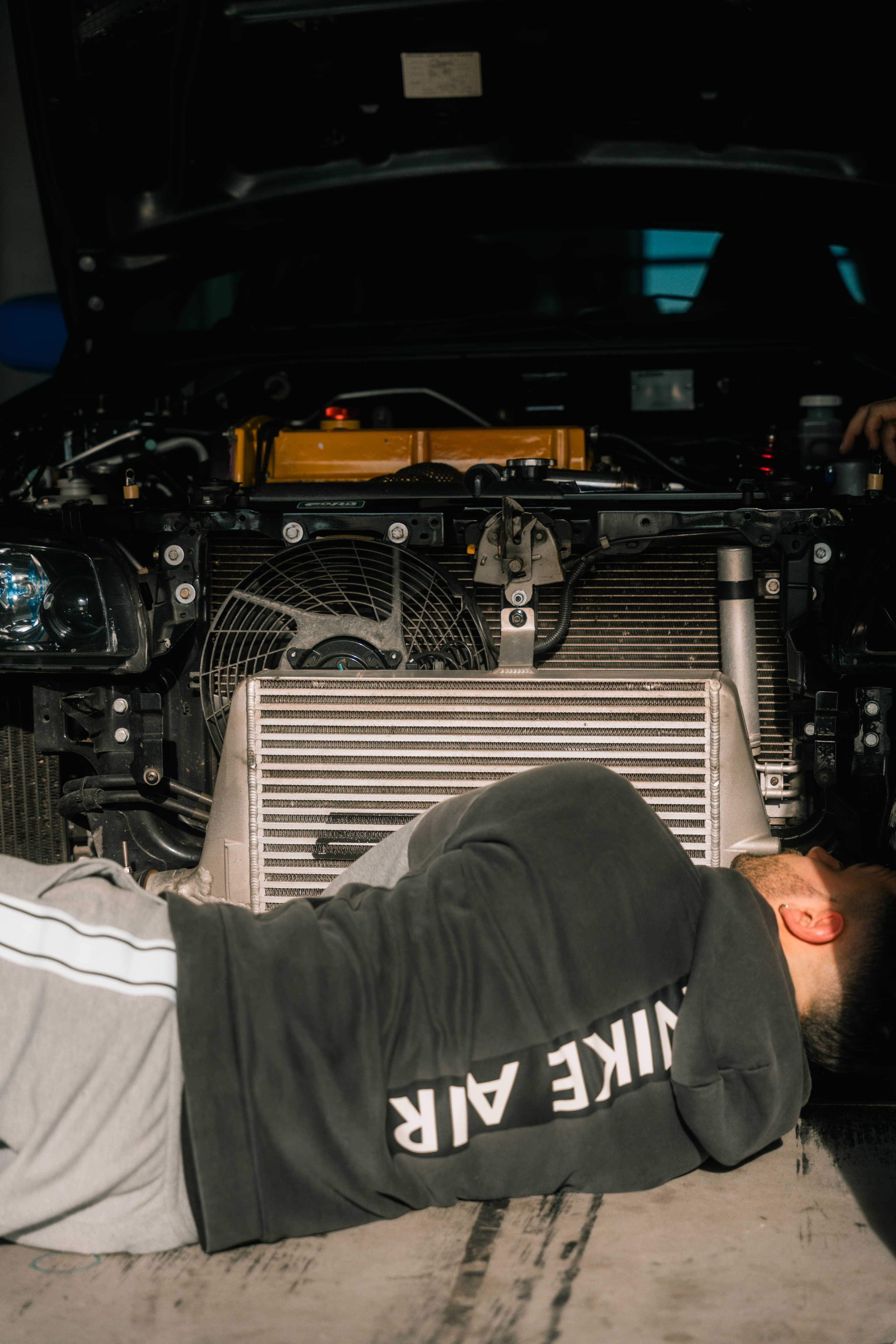 Mechanic servicing a car radiator and cooling system in a workshop