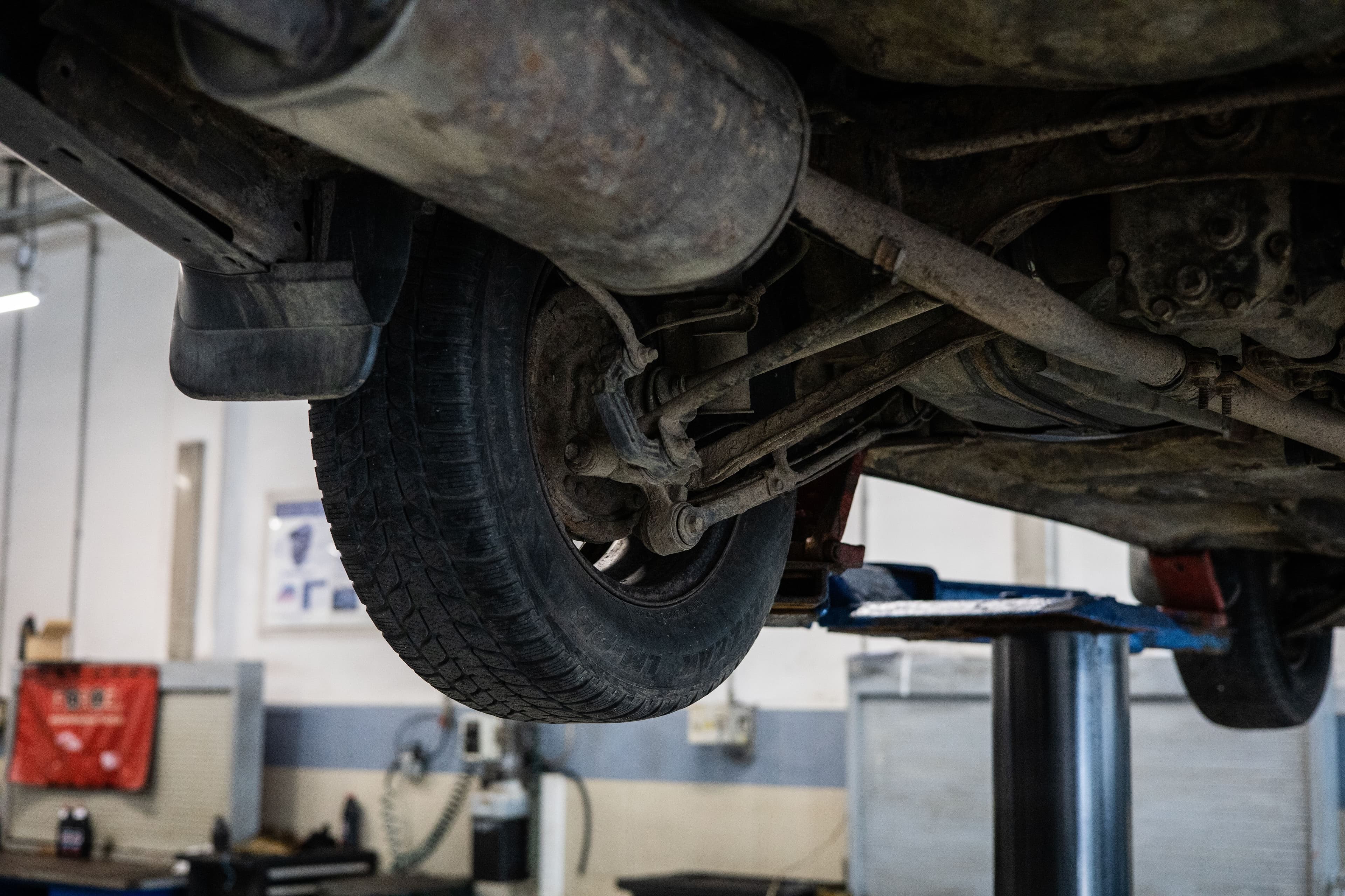 Close-up inspection of a vehicle undercarriage and rear driveline components on a workshop lift